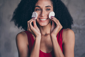 No retouch photo of good mood woman with afro hair dressed red top hold sponges on cheekbones...