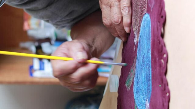 Vertical video of elderly woman painting as hobby