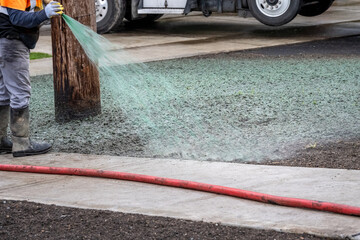 Professional hydroseeding, workman spraying a mix of grass seed and wood pulp from a big hose onto...