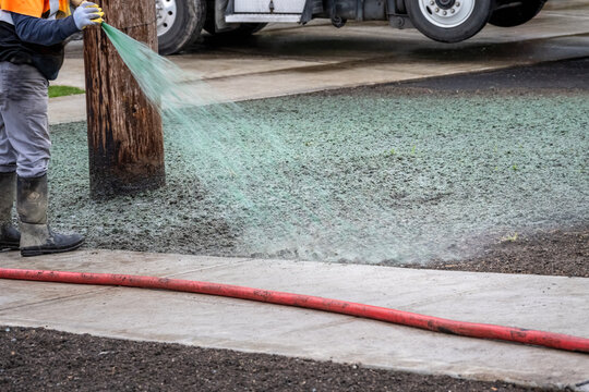 Professional hydroseeding, workman spraying a mix of grass seed and wood pulp from a big hose onto a freshly prepared dirt in a new residential community
