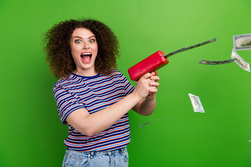 Profile photo of overjoyed cheerful lady hold money gun shoot dollar bills isolated on green color...