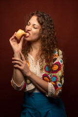 Hungry hispanic female bitting a scone. Vertical.
