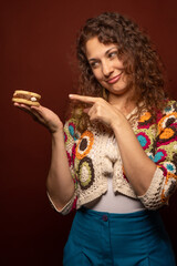 Latin Female pointing with finger a delicious pastry on her hand. Vertical, copy space.