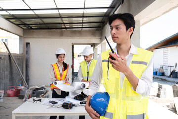 Portrait of a male engineer at a construction site using a walkie-talkie. Standing in charge of planning a construction project in formal attire, wearing a hard hat, a successful civil engineer.