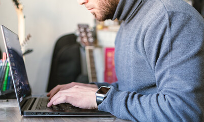 Hombre apuesto y profesional trabajando en la computadora portátil desde su hogar.