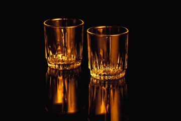 Black and orange isolated empty Whiskey drinking crystal glasses with reflections