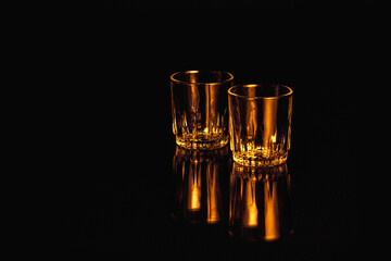 Black and orange isolated empty Whiskey drinking crystal glasses with reflections and space for text