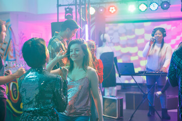 Girlfriends talking while relaxing on dancefloor at nightclub discotheque. Smiling women dancing...