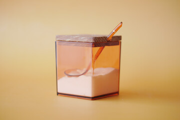 salt in a transparent jar on orange color background 