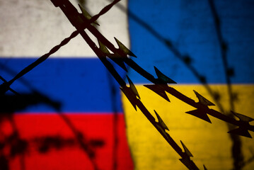Flaggen von Russland und Ukraine hinter dem Stacheldraht