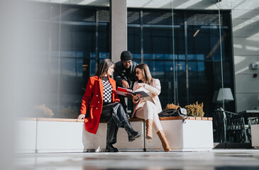 Three business professionals in stylish business attire engaged in a work discussion outside a...