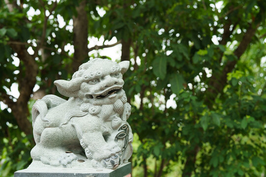 The image depicts a Chinese stone statue of a lion alongside a stone statue of a person, set against a backdrop of an ancient park, blending history and culture seamlessly