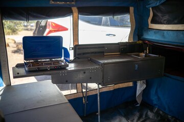 Cooking on a gas cooker at a campsite in the Forrest. Cooking outside on a blue camper trailer....