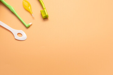 Template Personal Dental Oral Hygiene Kit. White Flexible Tongue Scraper, Toothbrush, Interdental Toothbrush For Cleaning Between Teeth On Peach Yellow Background. Space For Text. Horizontal Plane.