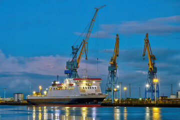 Three yellow and blue cranes at dusk seen in the port of Belfast, Northern Ireland