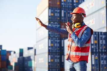African factory worker or engineer using walkie talkie and showing stop gesture to crane car in containers warehouse storage - obrazy, fototapety, plakaty