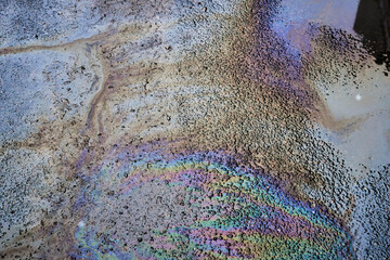 Abstract colored background of leaked gasoline on wet asphalt close-up