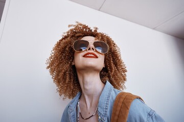 Joyful Smiling Woman: Portrait of a Beautiful Fashion Model with Curly Hair and Goggles, expressing...