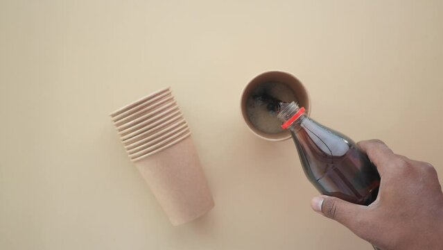 pouring soft drinks from bottle in paper cup 