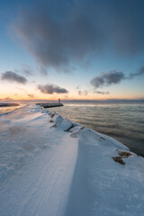 A beacon at the end of a breakwater with beautiful light of the polar night in the background on a cold winter day, Varanger Peninsula, Vestre Jagobselv, Northern Norway