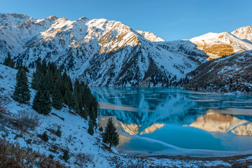 Mountain lake in the vicinity of the Kazakh city of Almaty and snow-covered mountains in the early morning