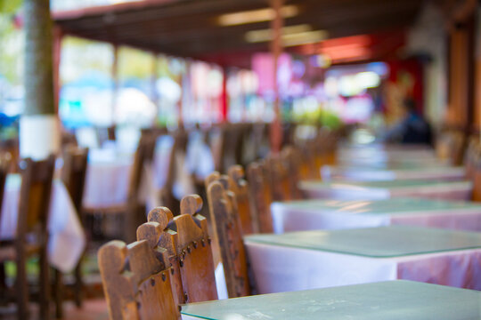 Restaurant in Guatape with old wooden chairs and tables in a row with bokeh effect. Colombia