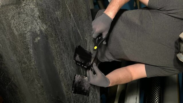 carbon fiber. cutting carbon fiber with scissors. vertical video. slow motion video. High quality video in 4K format.