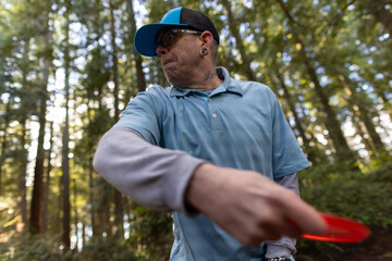 Close up shot of a man on the run up to throwing a driver disc on a disc golf course on the Kitsap Peninsula