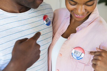 Biracial woman and African American man show their 'Vote' badges