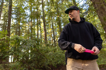 Medium shot of a man on the wind up to throwing a driver disc on a disc golf course in the forest...