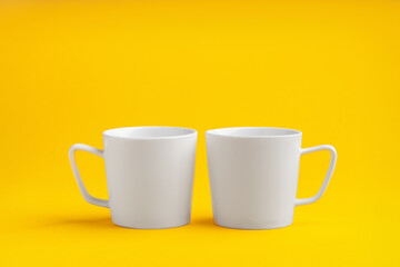Two mugs on yellow studio background close up