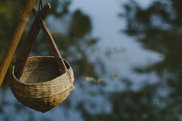Woven bamboo water bucket on blurred natural light background.