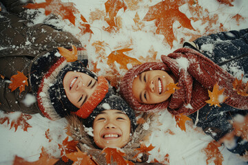 Happy family rolling in late autumn snow with orange leaves