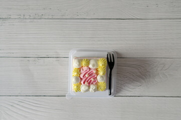 Closeup of Beautiful Pastel Rainbow Cake and a black plastic fork on white wooden table with blurred bokeh background at Thailand.