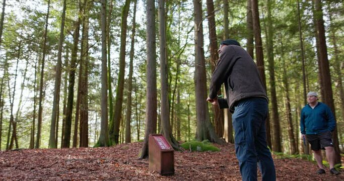Medium shot of a man throwing a driver disc forehand style while playing disc golf in the Pacific Northwest forest in slow motion at 120 fps