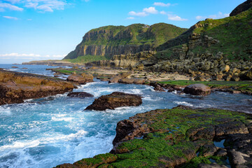 Gorgeous coastline with amazing cliffs and rocks, green lawn and sea grass covered on it, at...