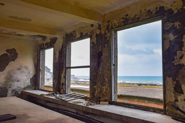 Inside abandoned old factory with three huge windows, and ocean in the front, in Jinguashi, New Taipei City, Taiwan.