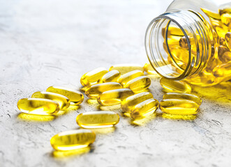 Omega 3 capsules scattered from transparent plastic medicine bottle