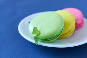 Colorful macaroons on a white plate on a blue background