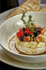 Baked camembert with berries and nuts in a plate. Photo for the menu