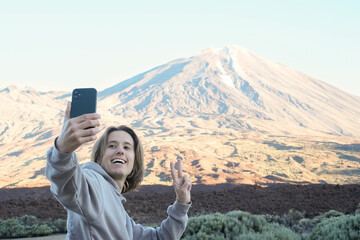 Young man with long hair Taking a Selfie With Teide Mountain in the Background