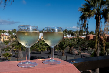 Glasses of cold white wine on roof terrace served outdoor in Corralejo, Fuerteventura in sunny day