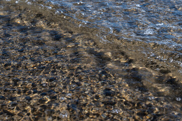 Crystal clear sea water texture with glare from the sun, wallpaper