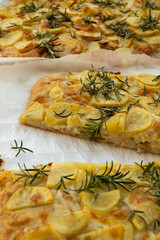 Fresh baked focaccia or pala romana pizza with potato vegetables and rosemary in bakery in Parma,...