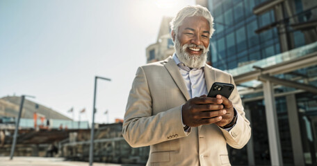 A man in a suit is smiling while looking at his phone