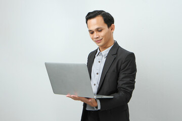 Happy asian indonesian business man in suit holding laptop computer on isolated background