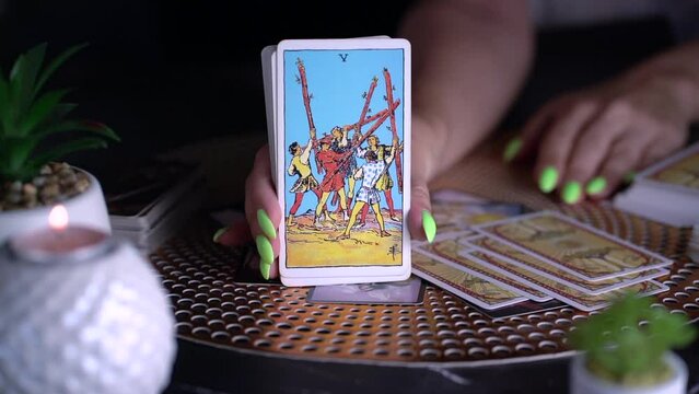 Fortune teller woman showing five of wands , reading a future by tarot cards. Esoteric concept, fortune telling and predictions. Slow motion