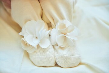 The legs of a small newborn baby. Light-colored clothes with a bow