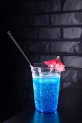 Blue lemonade with ice cubes in a plastic glass