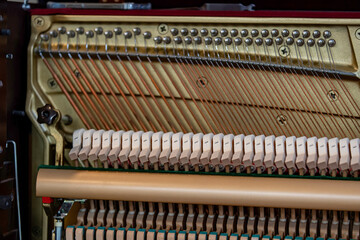 Close-up shallow focus image of the internal mechanisms of an upright piano. It gives a feeling of luxury, beauty, classic, sophistication, elegance. Image can be use for various topics about  music.